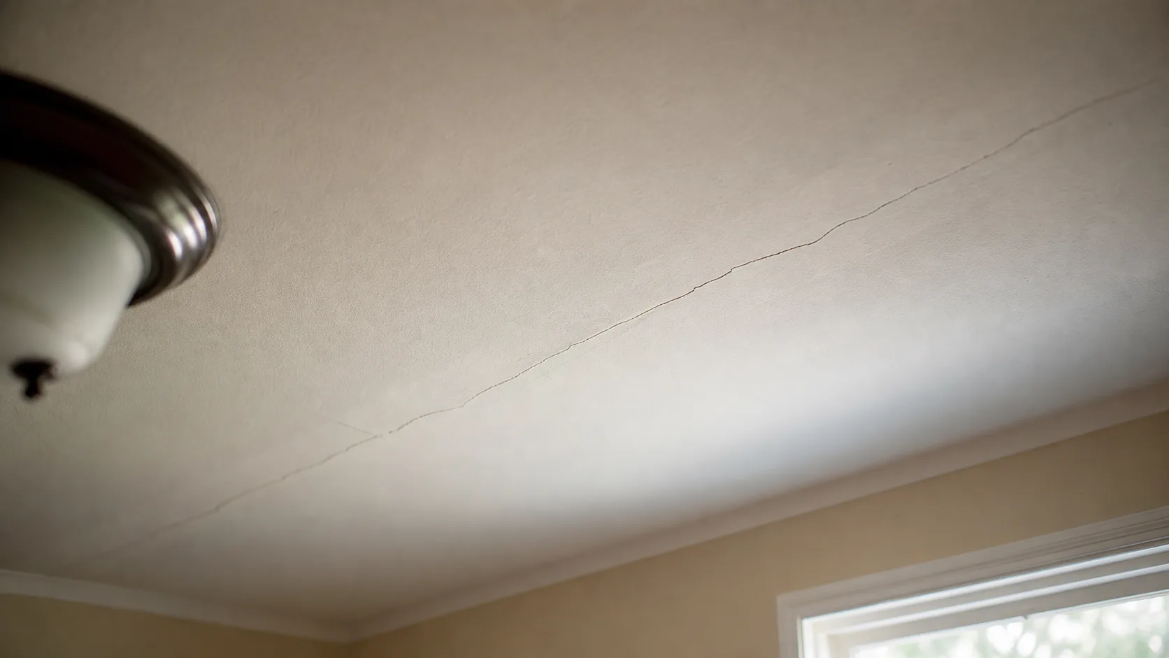 Hairline crack along a ceiling joint before repair.