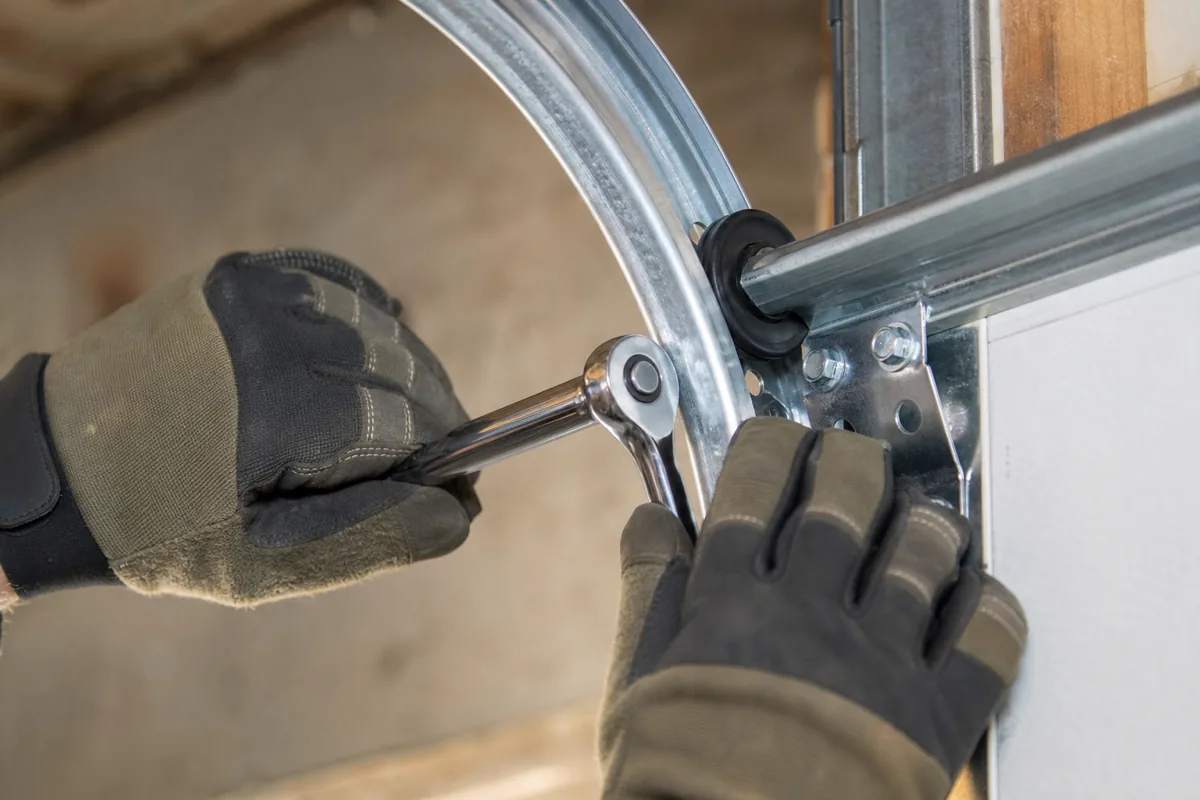 Loosening the track bracket bolts to realign a slipped garage door roller.