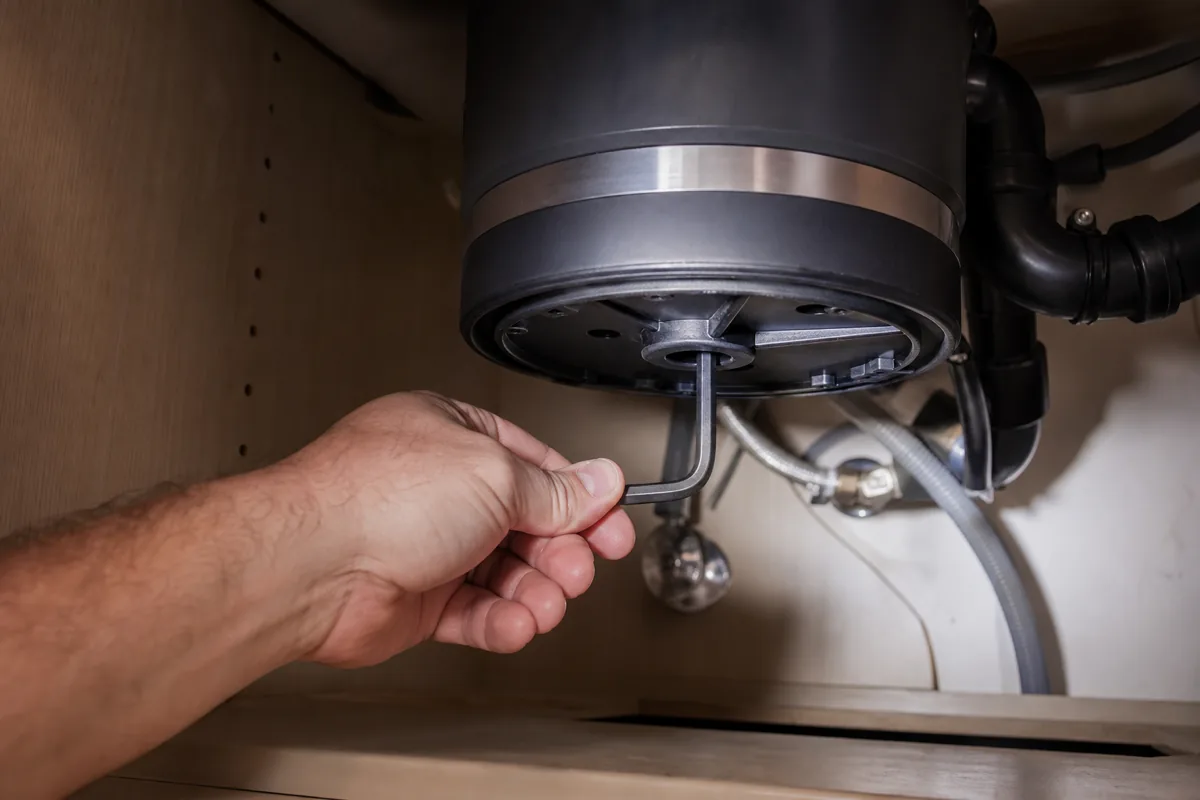 Using a hex key to clear a jammed garbage disposal flywheel.